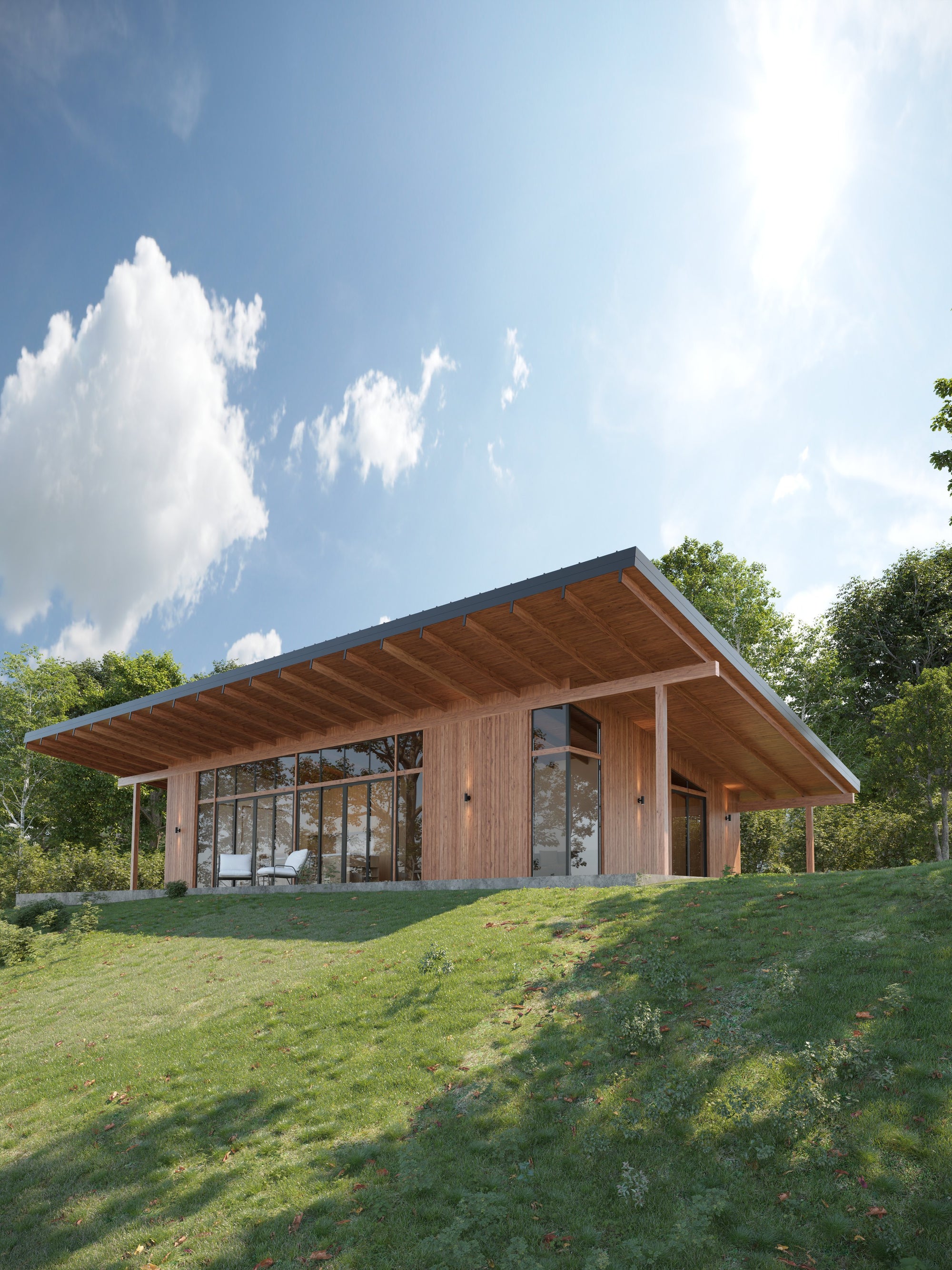 The Angle (2.2): glazed facade and deep roof overhangs on a grassy hill, afternoon light